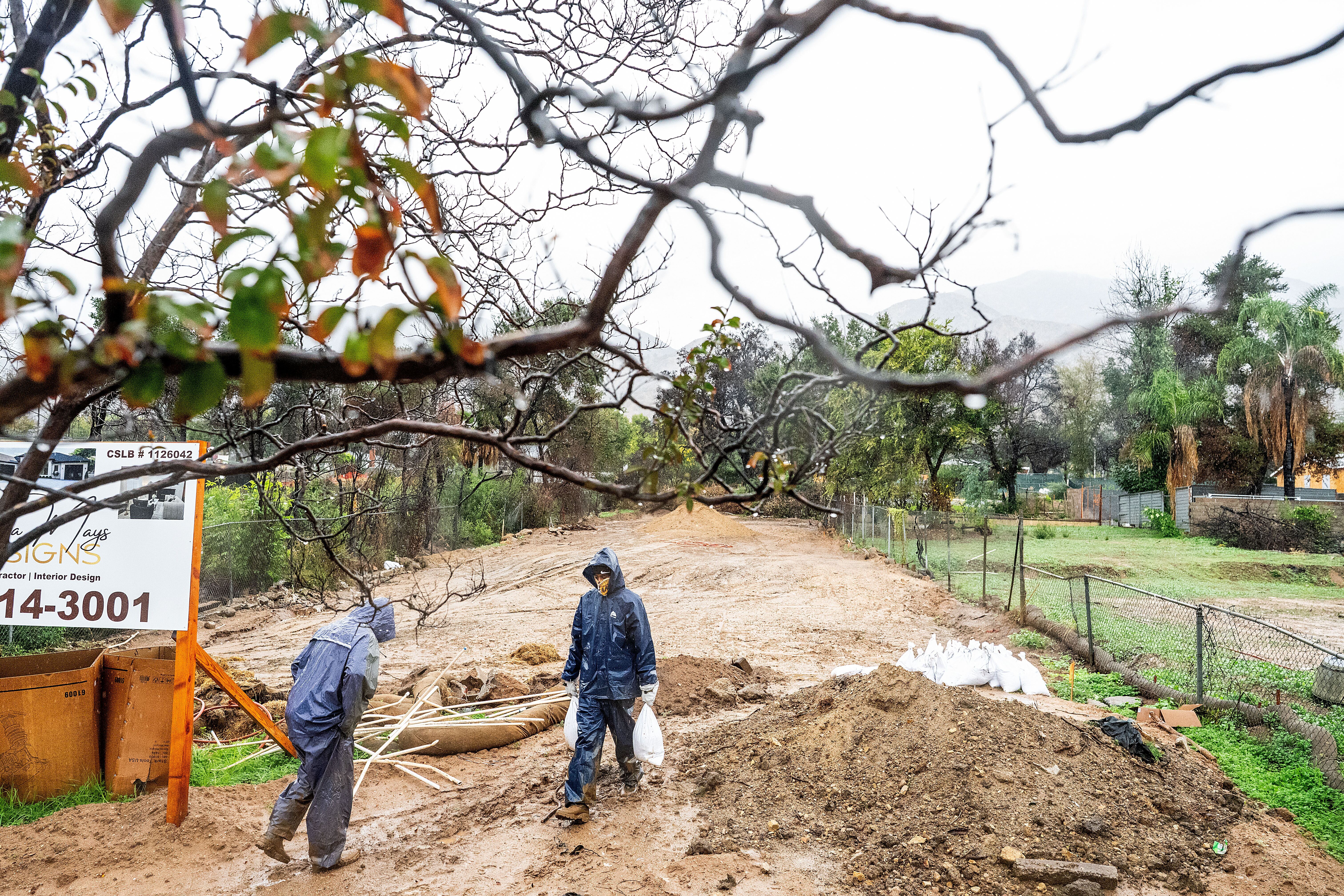 James Jones carries sandbags while trying to prevent water from running off a property scorched in the Eaton Fire in Altadena, Calif., as the region remains under flash flood warnings on Saturday.